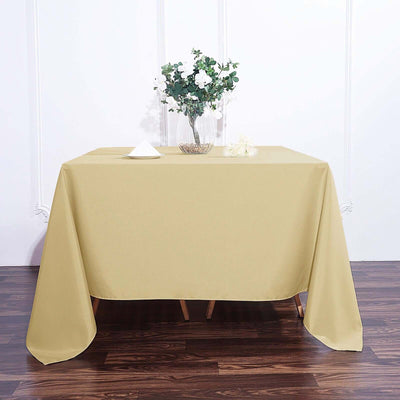 Beige tablecloth draped over a wooden table with a floral centerpiece.