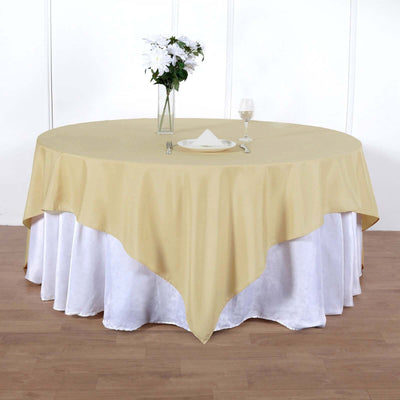 Round table with beige linen and white skirt, set with plate and glass.