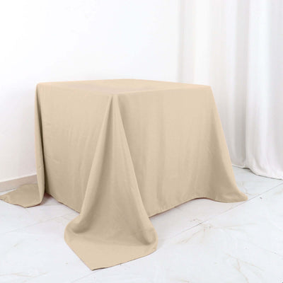 Beige tablecloth draped over a table against a plain backdrop