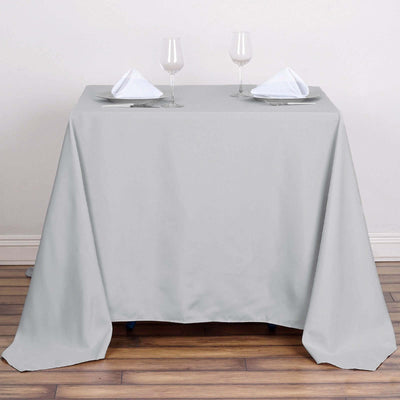 Gray tablecloth draped over a table with glasses and folded napkins.