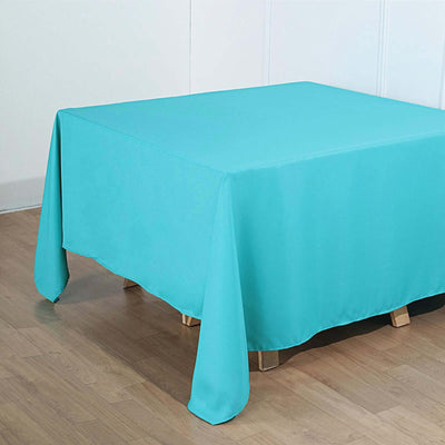 Turquoise tablecloth draped over a table with wooden legs.