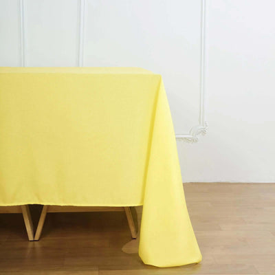 Yellow tablecloth draped over a wooden table in a bright interior setting.