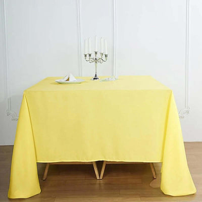 Yellow tablecloth draped over a table with a candle holder and decorative items.