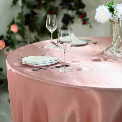 Elegant table setting with pink tablecloth, wine glasses, and floral centerpiece.