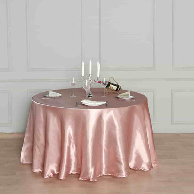 Elegant round table set with pink satin tablecloth and dinnerware.