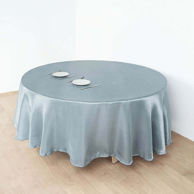 Round table covered with a light blue satin tablecloth set with two plates.