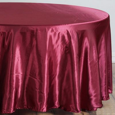 Burgundy round tablecloth with a glossy finish on a wooden surface.