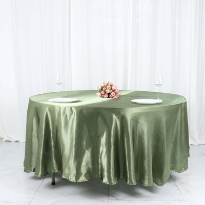 Elegant green satin tablecloth with floral centerpiece and wine glasses.