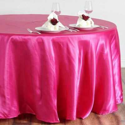Pink satin tablecloth draping over a round table set for dining.