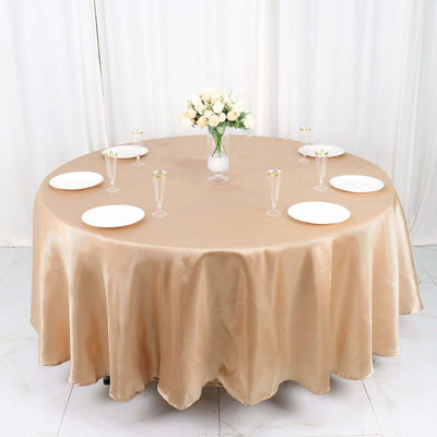 Elegant round table set with champagne flutes and white plates, adorned with flowers.