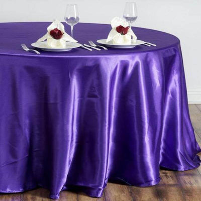 Purple satin tablecloth draped over a round table set for dining.