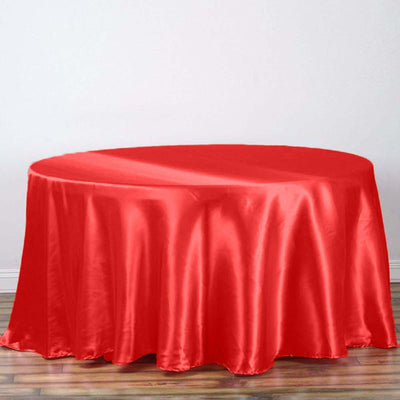 Red satin tablecloth draped over a round table in a bright setting.