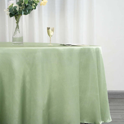 Elegant light green tablecloth draped over a table with a vase and glass.