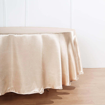 Elegant champagne satin tablecloth draping over a round table.