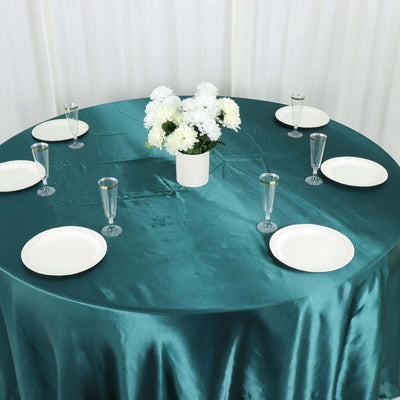 Round teal table setting with plates, glasses, and a floral centerpiece.