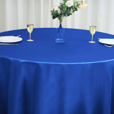 Blue tablecloth on a round table with glassware and a vase of flowers.