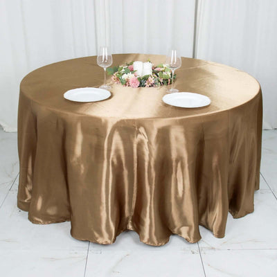 Round gold tablecloth with plates and glasses on a decorated table.