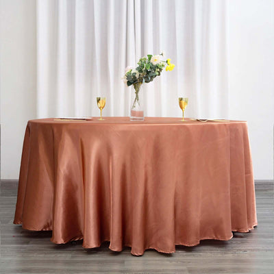 Elegant round table with a copper tablecloth, adorned with a vase and glasses.