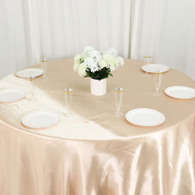 Elegant round table set with white plates and champagne flutes, adorned with flowers.