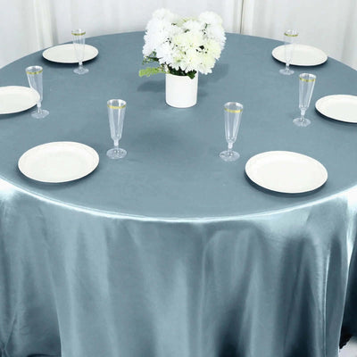 Elegant round table set with plates and glasses, adorned with a floral centerpiece.