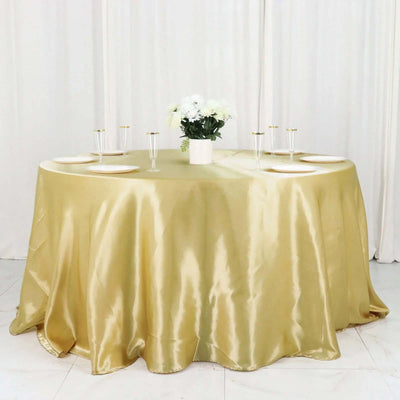 Elegant gold satin tablecloth draped over a round table with floral centerpiece.