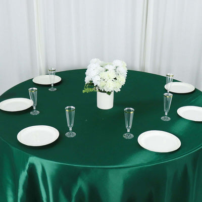 Elegant green table setup with white plates and floral centerpiece.