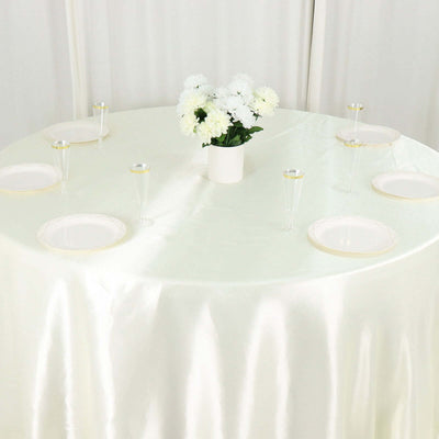 Elegant round table set with white plates and floral centerpiece.