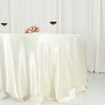 Elegant ivory satin tablecloth with pink rose bouquet and wine glasses.