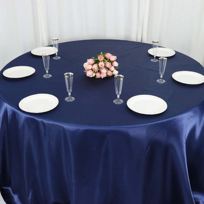 Round navy tablecloth with plates and glasses set for dining, adorned with a floral centerpiece.