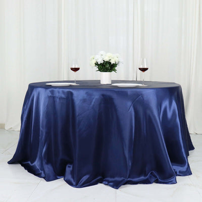Round navy satin tablecloth with floral centerpiece and wine glasses.