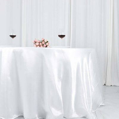 Elegant white satin tablecloth with roses and wine glasses.