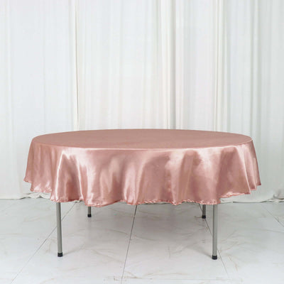 Round pink satin tablecloth on a table against a white backdrop.