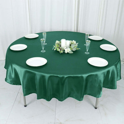 Round green tablecloth with plates and glasses on a round table.