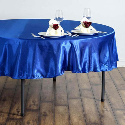 Blue satin tablecloth draped over a round table set for dining.