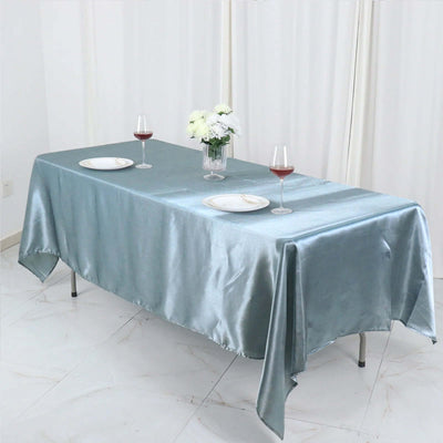 Elegant satin tablecloth in soft blue, set for dining with wine glasses and flowers.