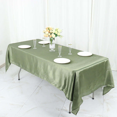 Elegant green tablecloth on a dining table with plates and floral centerpiece.