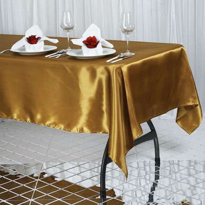 Elegant gold tablecloth set for dining with glasses and decorative napkins.