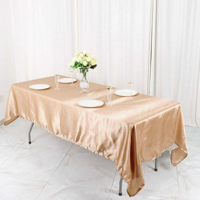 Elegant gold satin tablecloth draped over a table with floral centerpiece and dinnerware.