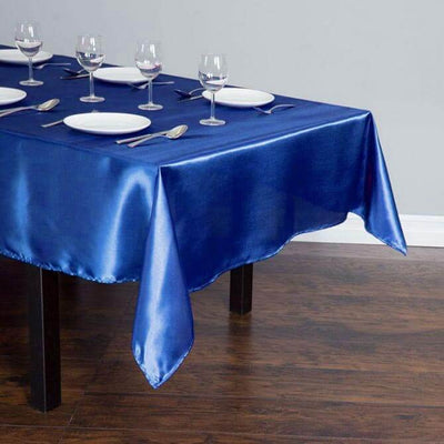Blue satin tablecloth draped elegantly over a dining table with plates and glasses.