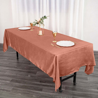 Rust orange tablecloth draped over a dining table set with plates and glasses.
