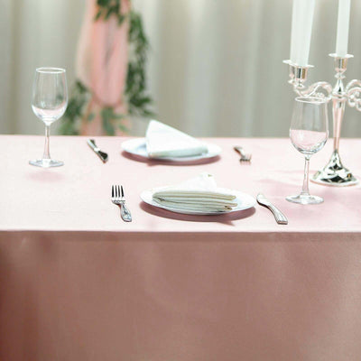 Elegant dining setup with pink tablecloth, plates, glasses, and silverware.