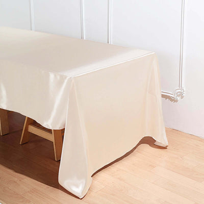 Cream satin tablecloth on a wooden table against a white wall.