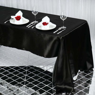 Elegant black tablecloth with white dinnerware and rose centerpiece on a stylish setting.