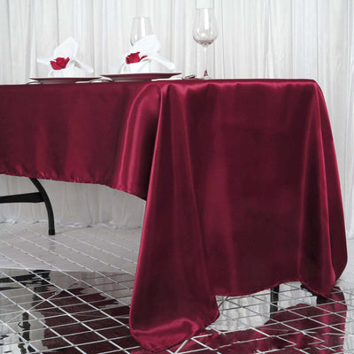 Burgundy satin tablecloth draping elegantly over a dining table.