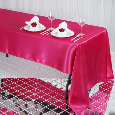 Elegant pink satin tablecloth set for dining with rose and napkin decor.