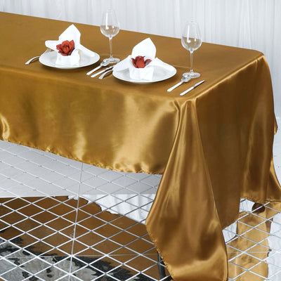 Elegant gold satin tablecloth draped over a table with fine dining setup.