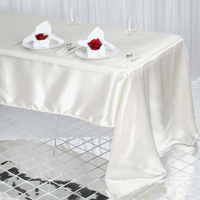 Elegant satin tablecloth draped over a modern table setting with roses.