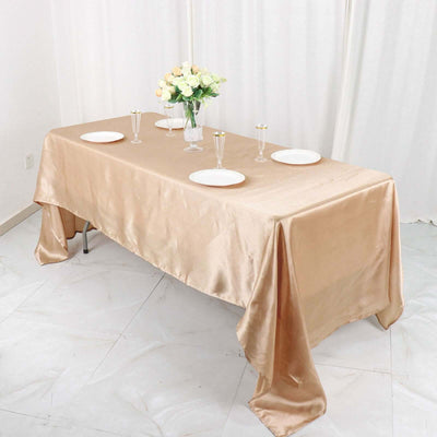 Elegant beige satin tablecloth draped over a table set for dining.