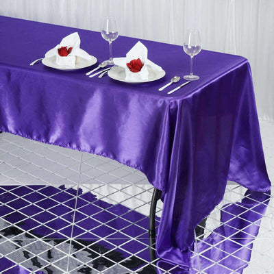 Purple satin tablecloth draped over a table set with elegant dinnerware.