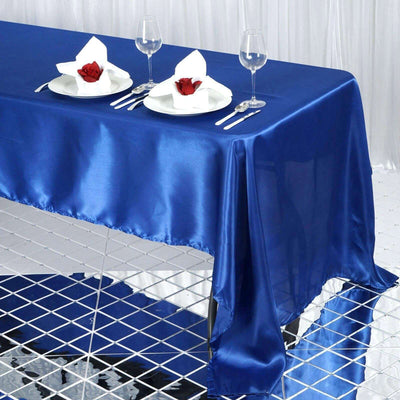 Blue satin tablecloth draped elegantly over table with plates and rose decorations.